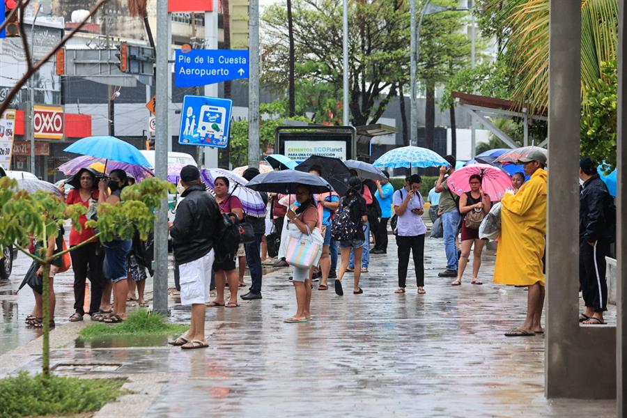 Personas caminando en la lluvia con sombrillas.