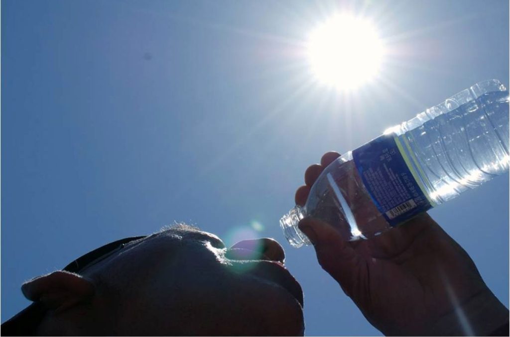Persona tomando agua bajo el sol