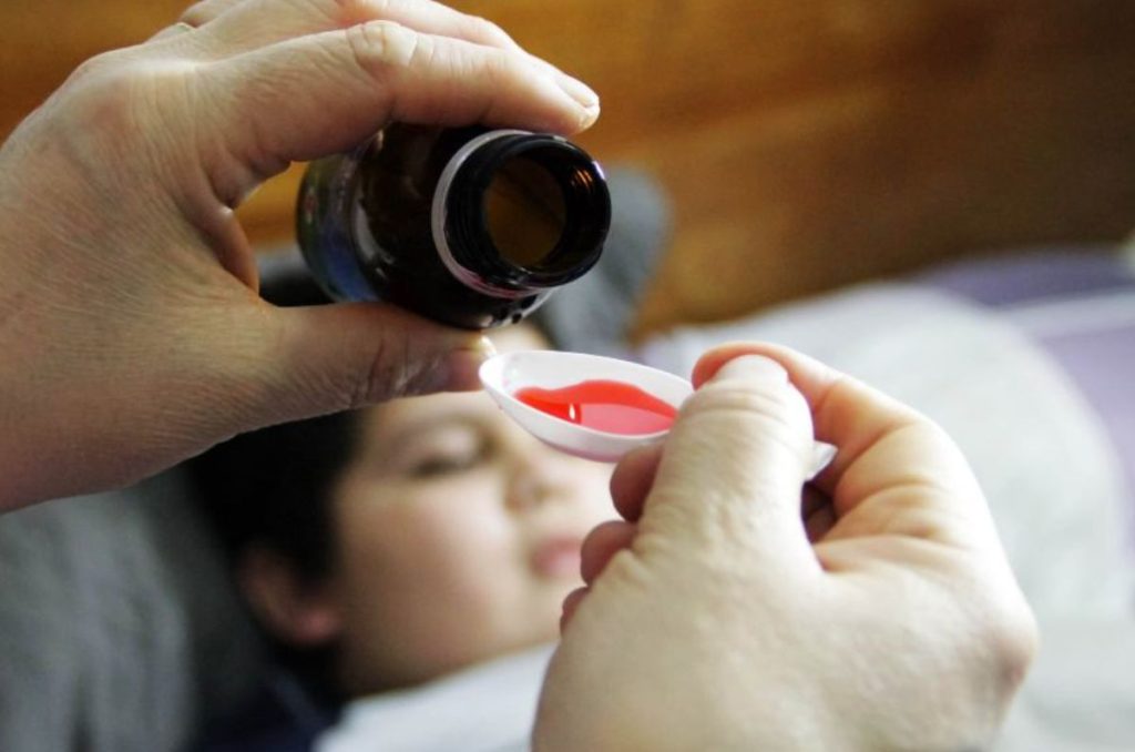 Niño enfermo con jarabe para la tos