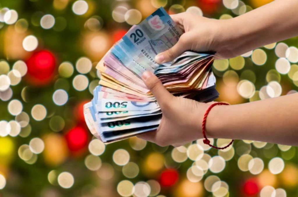 Manos con dinero en decoración de navidad, representando pago de aguinaldo.