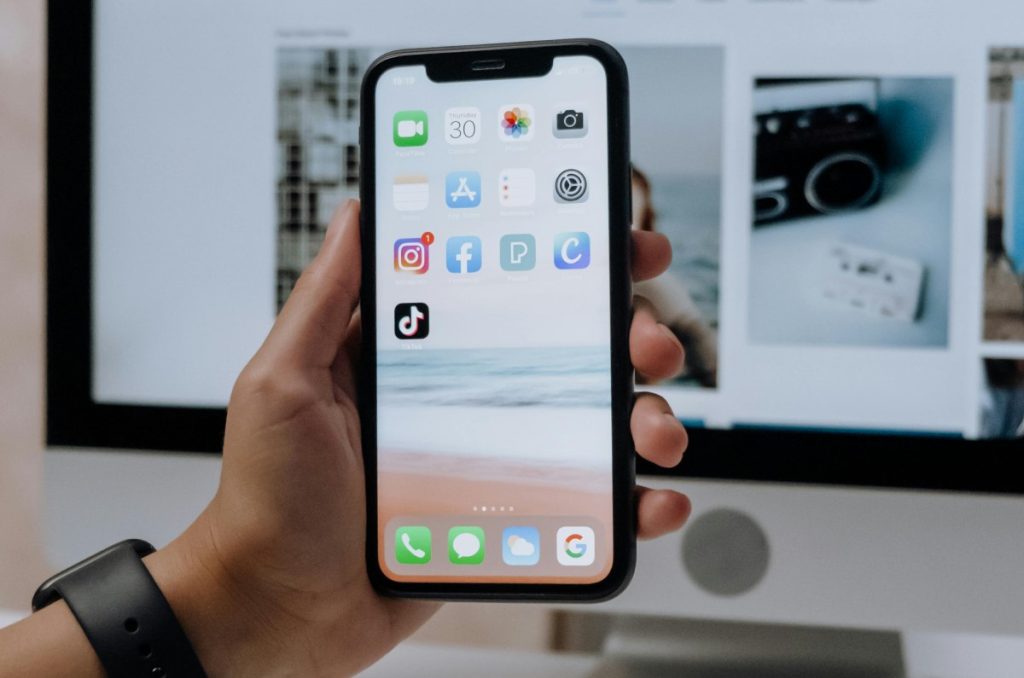 Usuario sostiene celular que muestra varias apps de redes sociales, entre ellas TikTok.