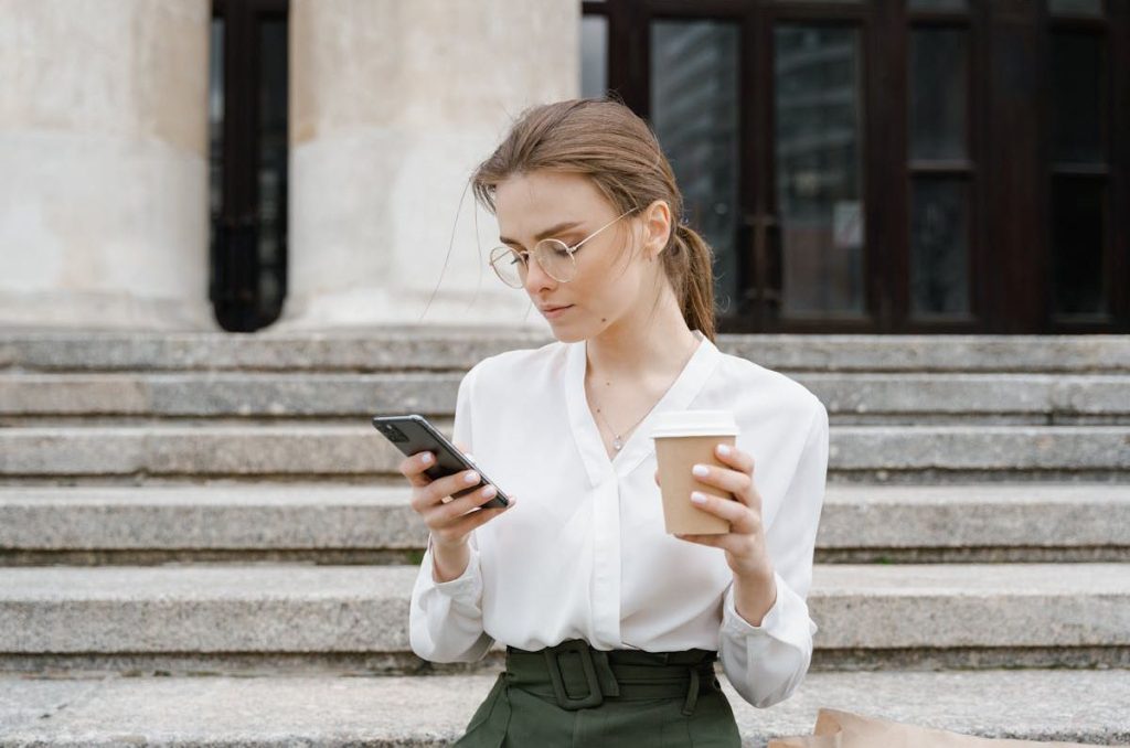 Una mujer observa su celular en el exterior.